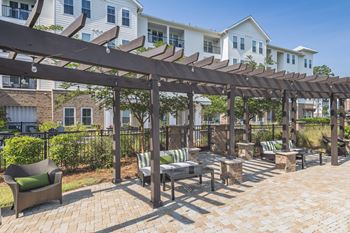 A patio with a wooden pergola and furniture.